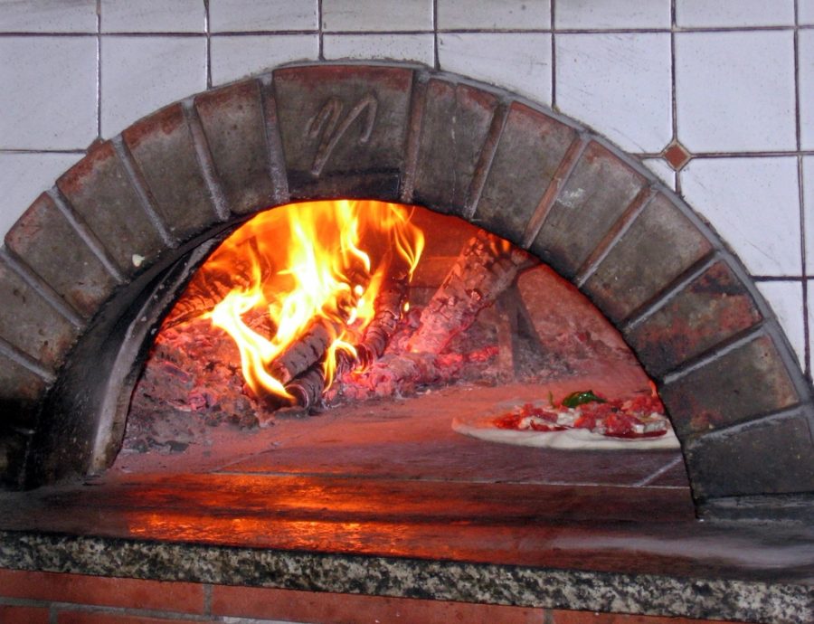Forno a lenha aceso, com a chama iluminando a câmara